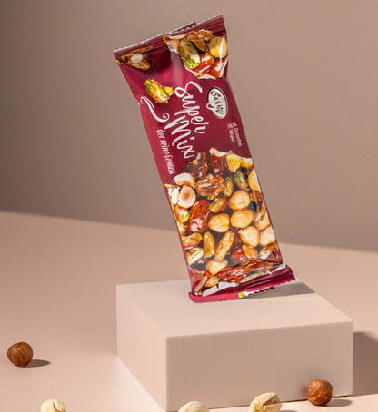 A red-packaged Granio Super Mix snack bar featuring a visible blend of dried nuts and fruits, balanced on a small beige pedestal.